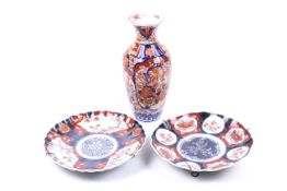 Three early 20th century Imari pattern china items. Including a vase and two plates. Max.