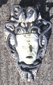 A weathered wall hanging fountain head mask depicting Medusa. With metal snakes in her hair.
