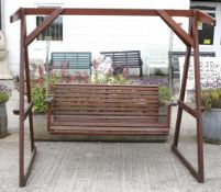 A garden swinging chair. Constructed of stained wood with metal chains, missing screws and nuts.