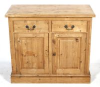 A pine cupboard. Having two drawers above two panelled doors raised on a plinth base.