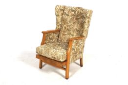 An upholstered wingback armchair. With shaped wooden arms and square supports.