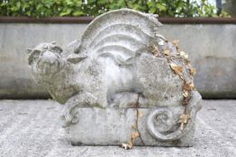 A weathered reconstituted stone model of a griffin. In a crouched position.