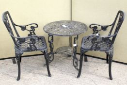 A vintage cast metal circular table and two chairs.