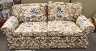 A pair of cream floral pattern three seater sofas. With scroll arms and raised on casters.