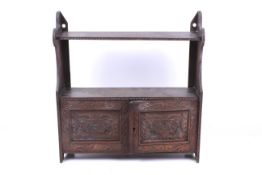 A 20th century hanging bookshelf. Heavily carved, having a pair of panelled doors, H55.5cm x W52.