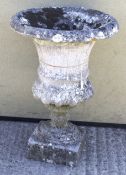 A reconstituted stone garden urn. Having ribbed decoration, on a square base.