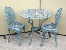 A vintage cast metal circular table and two chairs.