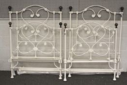 Two cast iron single bed frames. Painted white with scrolling decorations, headboards H125.