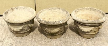 A set of three reconstituted stone garden pots. Of tapering form with ribbon and swag decoration.