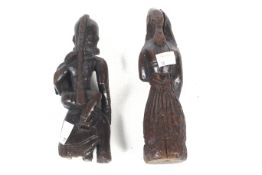 A pair of carved wooden figurines. Modelled as deities, one of a woman holding a child, H18.