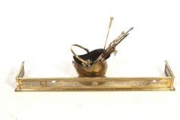 A brass fender and a selection of fire tools.