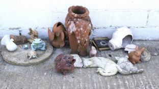 A collection of terracotta and stone garden items including a terracotta fish ornament.