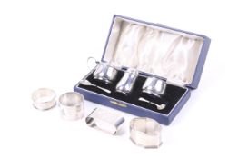 A silver round three piece cruet set and four napkin rings.