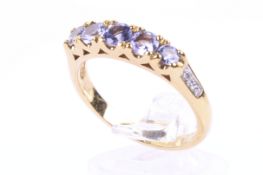 A modern tanzanite five stone ring with tiny diamond shoulders.