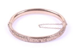 An early 20th century gold part foliate engraved hollow hinged bangle.