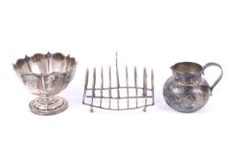 A silver toast rack, a pedestal sugar bowl and a milk jug.