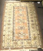 A Persian style wool rug. Multi geometric borders, central medallion on a peach ground.