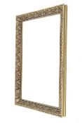 A large antique style gilt framed bevelled edge wall mirror. The frame decorated with foliage.