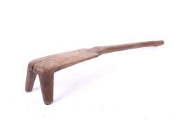 A Tribal low wood tripod stool. On two short legs, the third elongated, L79cm.
