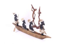 An African wood carving of figures in a canoe and two further figures.