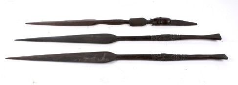 Three African wood spear heads. One carved with a head, the other with rows of lines. Largest L74cm.