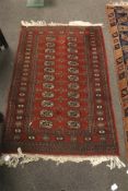 A Persian style red brown ground wool rug. Multi geometric borders with black outlines.