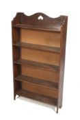 An Edwardian oak freestanding bookcase. Having five fixed shelves with a shaped gallery above.