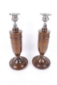 A pair of early 20th century turned wooden candlesticks. Mounted on circular bases.