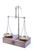 A set of Victorian Avery brass balance scales. Raised on a mahogany base with drawer and contents.