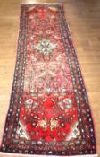 An Iranian red ground wool runner carpet.