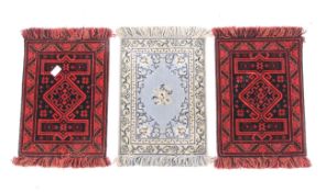Three woollen salesman 'sample' rugs. Two coloured red with a geometric pattern, 31.5cm x 22.