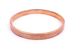 A late Victorian 9ct rose gold bangle. Engine turned pattern throughout.
