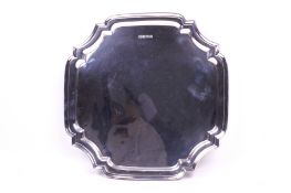 A silver quatrefoil footed tray. With stepped rim, raised on four short scroll feet.