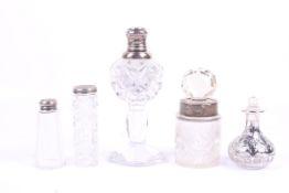 A group of five cut glass and silver and white metal topped perfume bottles.