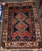 A Persian style woollen rug. Multiple geometric borders central medallion on a dark blue ground.