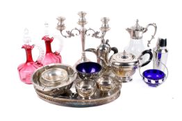 A pair of cranberry glass ewers and stoppers and a quality of silver-plated items
