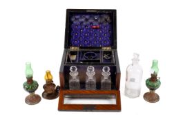 A drop front Victorian mahogany jewellery box with assorted glass bottles and miniature oil lamps.