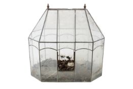 An indoor plant glass terrarium in the shape of a green house.