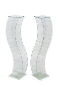 A pair of glass stands. Of serpentine form on a square base.