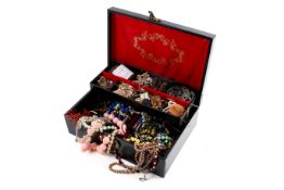A black jewellery box full of costume jewellery. Including assorted necklaces, brooches, etc.