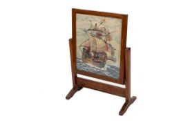 An early 20th century oak framed fire screen. With needle work ship under sail.