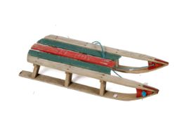 A scratch built vintage wooden sled. With red and green painted seat and metal skids, L89cm.