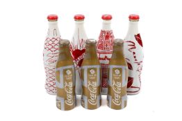 Seven sealed limited edition Coca Cola bottles.