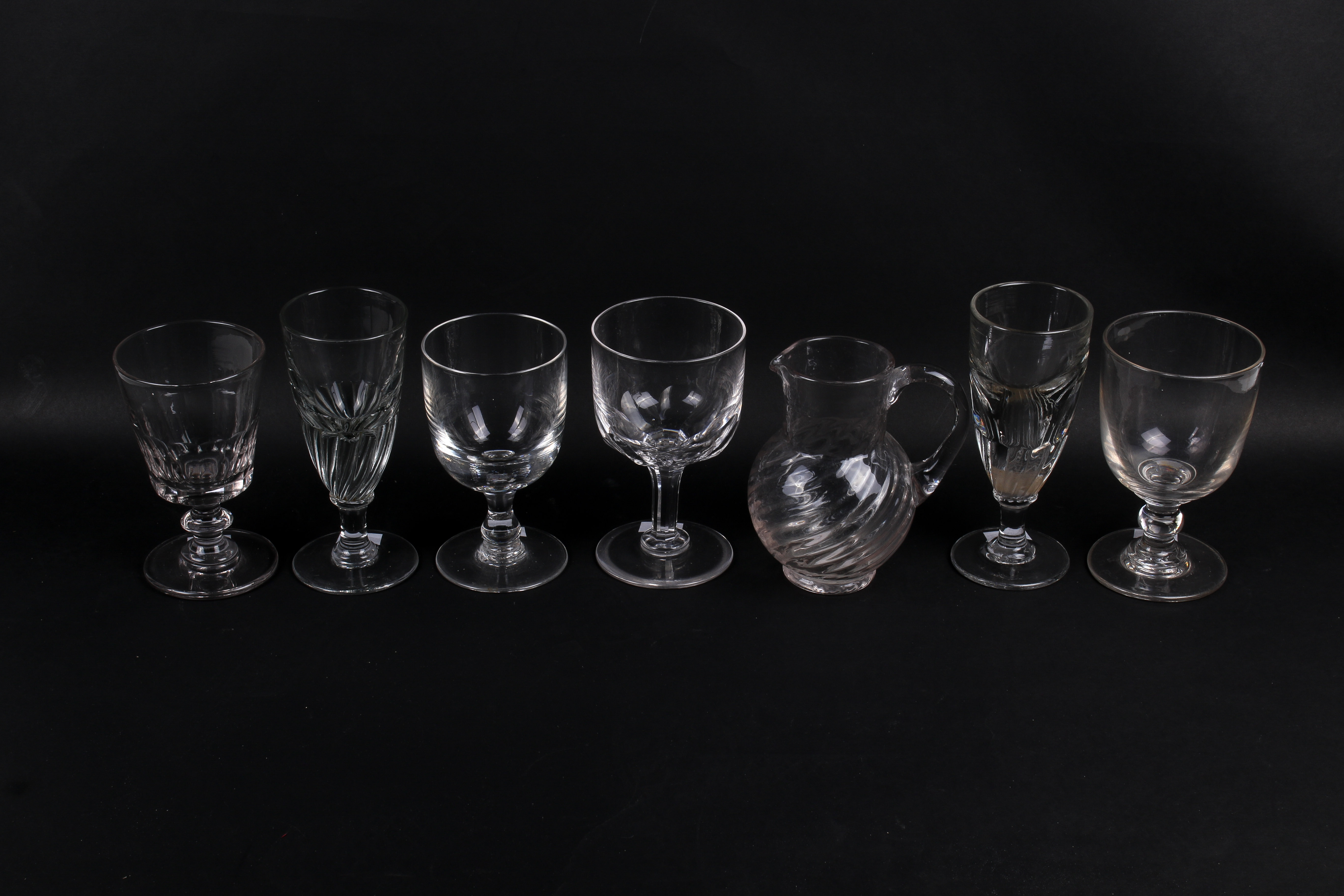 A collection of seven assorted glass items. Consisting of six drinking glasses and a jug. Max.
