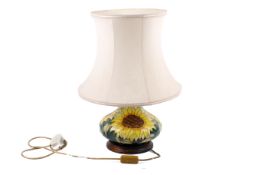 A contemporary Moorcroft pottery lamp with sunflower decoration. Raised on a circular wooden base.