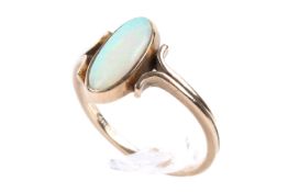 A 9ct gold and opal ring. The slender oval opal flanked by scrolls.