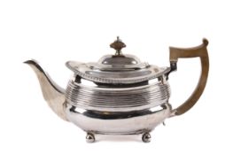 A Georgian silver teapot. With beaded rim over horizontal ribbing, raised on bun feet.