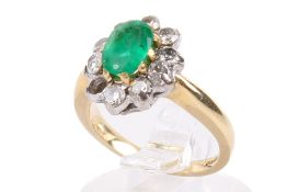 A modern 18ct gold, emerald and diamond oval cluster ring. Centred with an oval mixed-cut emerald .