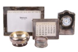 Two silver photograph frames, a table clock and a dish.
