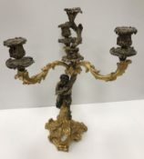 WITHDRAWN A gilt brass Rococo style candle holder as a satyr holding aloft three acanthus